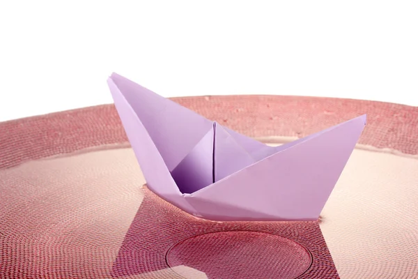 Color paper ship in water on pink plate, close-up — Stock Photo, Image