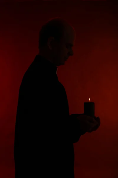 Portrét mladý pastor drží svíčku v ruce, izolované na černém pozadí — Stock fotografie