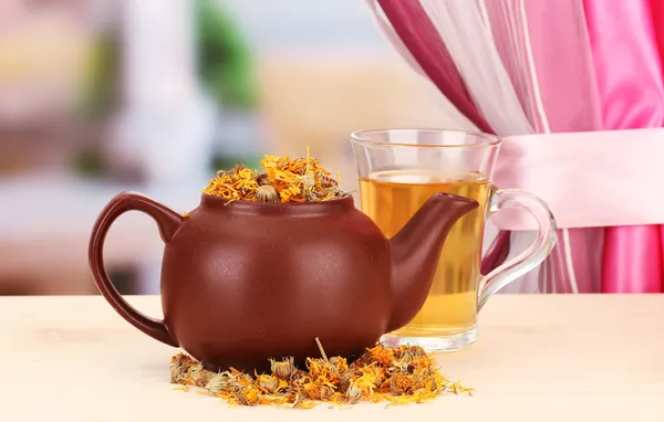 Dried herbs in teapot on wooden table, on bright background. Conceptual photo of herbal tea. — Stock Photo, Image