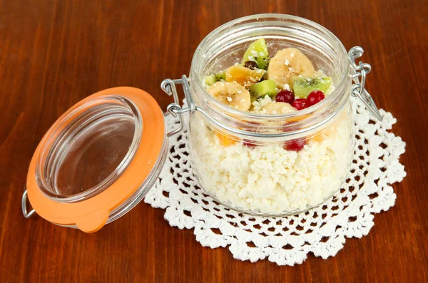 Queso de cabaña en botella de vidrio con frutas exóticas, sobre fondo de madera — Foto de Stock