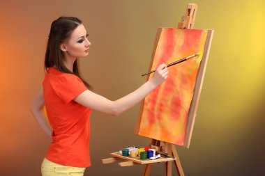 güzel bir genç kadın ressam anda, parlak renkli arka plan üzerinde