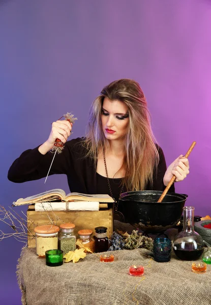 Halloween witch stirring in poison soup in her cauldron on color background — Stockfoto