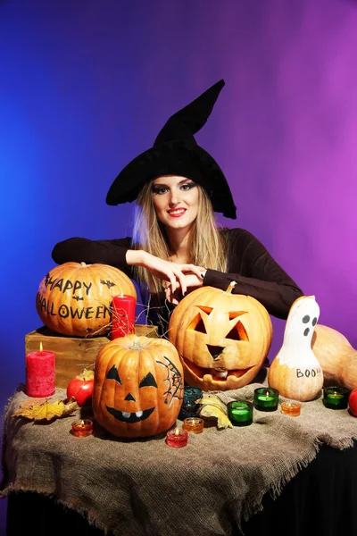 Halloween-Hexe mit Kürbissen auf farbigem Hintergrund — Stockfoto