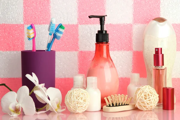 Аксессуары для ванны на полке в ванной комнате на фоне розовой плитки — стоковое фото