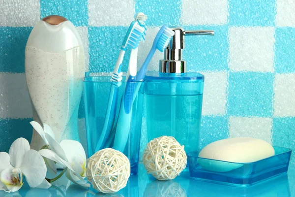 Аксессуары для ванны на полке в ванной комнате на фоне синей плитки — стоковое фото