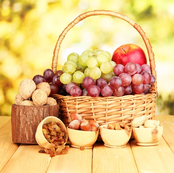 Grape in basket with nuts on wooden table — Stock Photo, Image