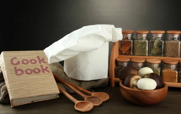 Složení s kloboukem a kitchenwear na stole na šedém pozadí šéfkuchaře — Stock fotografie