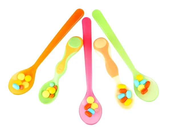 Plastic spoons with color pills, isolated on white — Stock Photo, Image