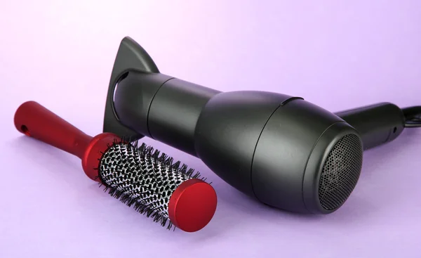 Hair dryer and comb brush, on purple background — Stock Photo, Image