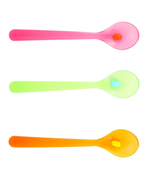 Plastic spoons with color pills, isolated on white — Stock Photo, Image