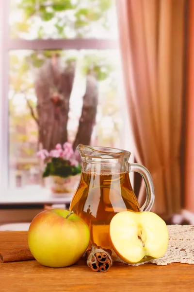 Full jug of apple juice and apple on wooden table on bright background — Stock Photo, Image