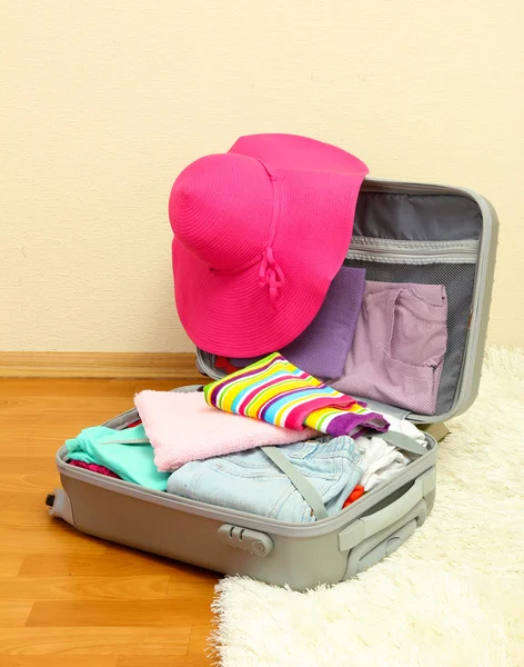 Open silver suitcase with clothing in room — Stock Photo, Image