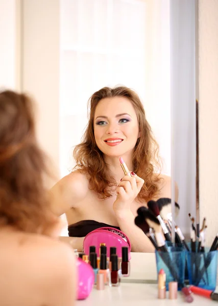 Joven hermosa mujer haciendo maquillaje cerca del espejo —  Fotos de Stock