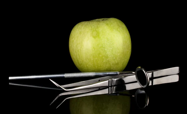 Pomme verte et outils dentaires isolés sur noir — Photo
