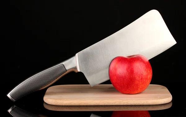 Червоне яблуко і ніж на обробній дошці, ізольовані на чорному — стокове фото