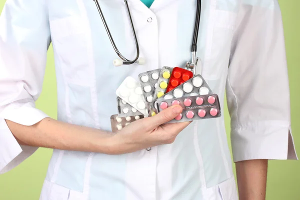 Close-up de mulheres médico mão segurando pílulas, em fundo de cor — Fotografia de Stock