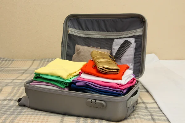 Offener grauer Koffer mit Kleidung auf dem Bett — Stockfoto