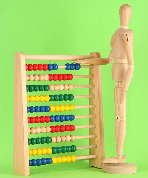Heldere speelgoed abacus en houten pop, op groene achtergrond — Stockfoto