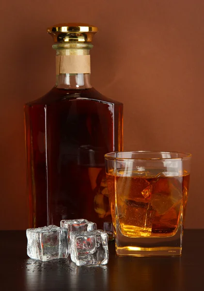 Şişe, bardak viski ve buz üzerinde kahverengi zemin — Stok fotoğraf