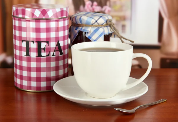 Банка и чашка чая на столе в номере — стоковое фото