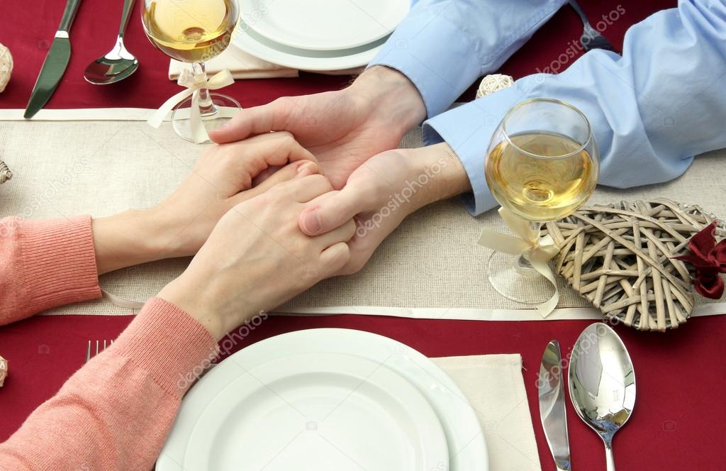 hands of romantic couple over a restaurant table