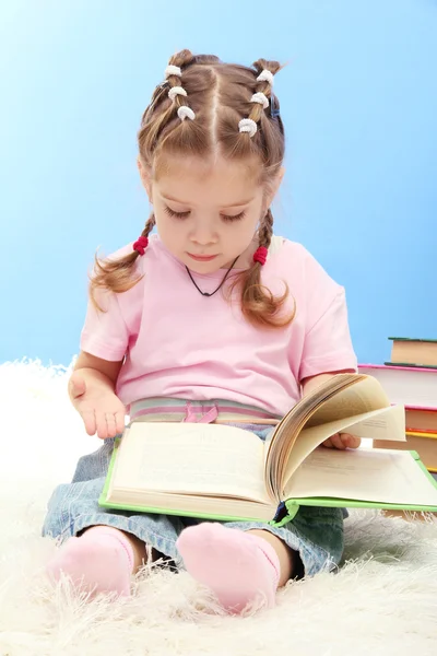 Mignonne petite fille avec des livres colorés, sur fond bleu — Photo