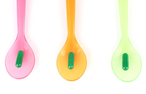Plastic spoons with color pills, isolated on white — Stock Photo, Image