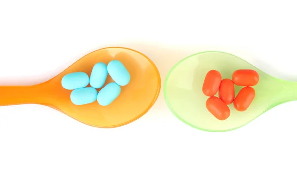 Cucharas de plástico con píldoras de color, aisladas en blanco — Foto de Stock