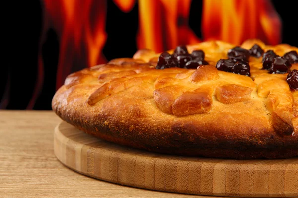 Sabroso pastel casero con mermelada, sobre mesa de madera sobre fondo de llama —  Fotos de Stock