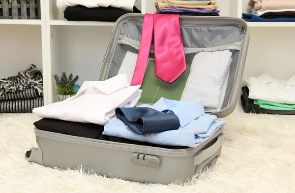 Offener grauer Koffer mit Kleidung im Zimmer — Stockfoto