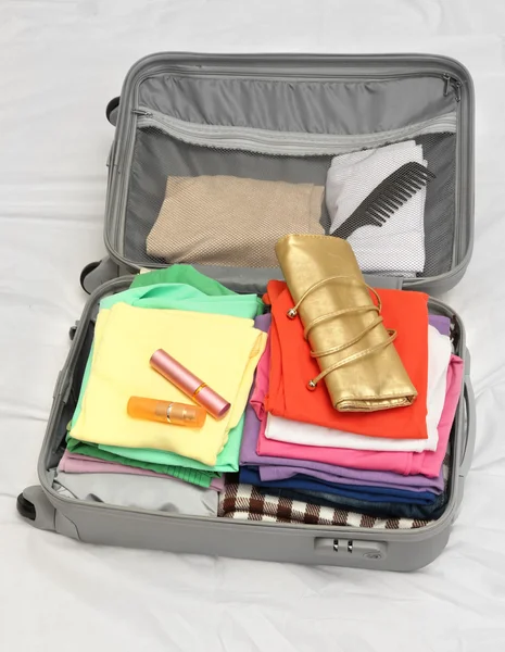 Valise ouverte grise avec vêtements sur le lit — Photo