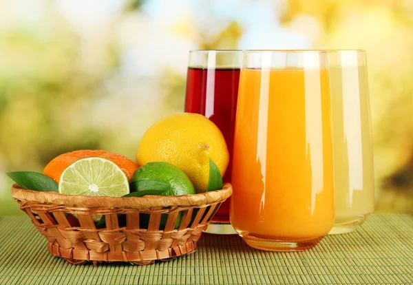 Glasses of juise with leafs and fruits on table on bright background — Stock Photo, Image