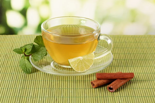 Xícara de chá com hortelã, limão e canela na mesa em fundo brilhante — Fotografia de Stock