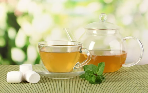 Чашка чая с мятой на столе на яркой баколе — стоковое фото