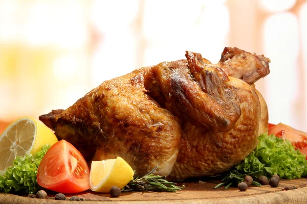 Whole roasted chicken with vegetables on plate, on wooden table in cafe — Stock Photo, Image