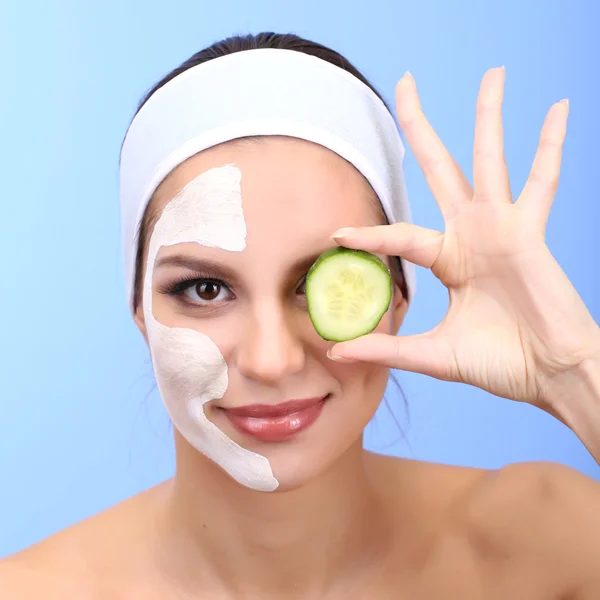 Jovem com máscara facial de barro, em fundo azul — Fotografia de Stock