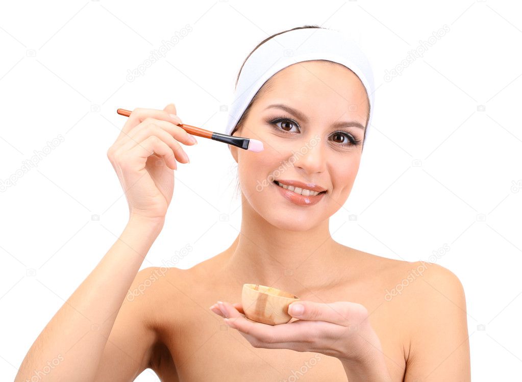 Young woman applying clay facial mask, isolated on white