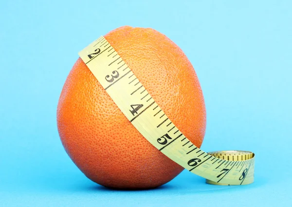 Arancione con nastro di misura su sfondo blu — Foto Stock