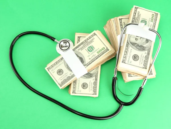 Healthcare cost concept: stethoscope and dollars on green background — Stock Photo, Image