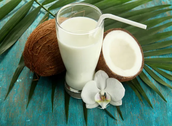 Cocos con vaso de leche, sobre fondo azul de madera — Foto de Stock