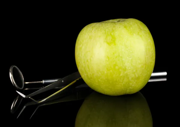 Grüner Apfel und Zahnwerkzeuge isoliert auf schwarz — Stockfoto
