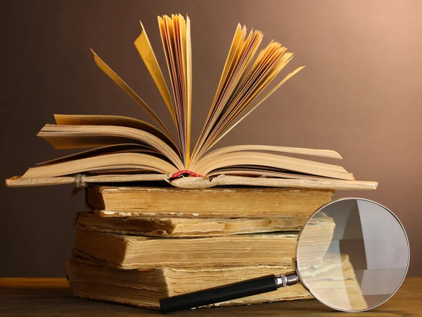 Magnifying glass and books on table — Stock Photo, Image