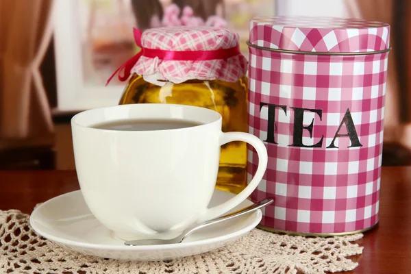 Jar and cup of tea on table in room — Stock Photo, Image