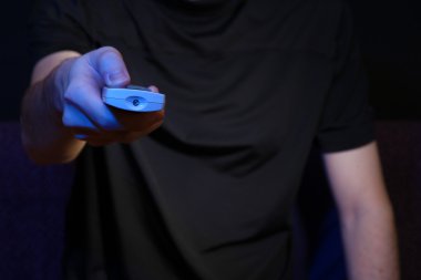 adam el bir tv uzaktan kumanda, koyu arka plan üzerinde tutarak