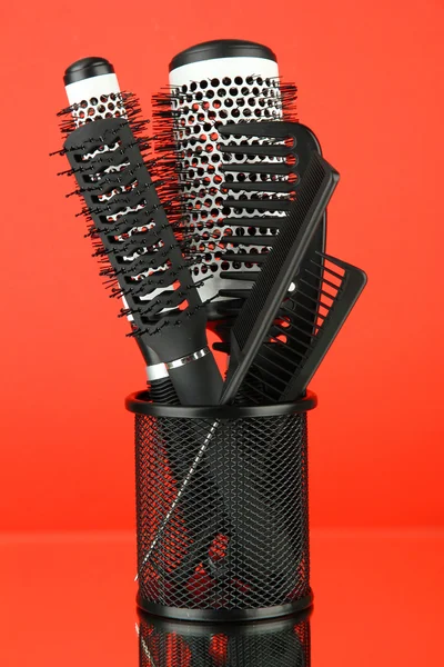 Cesto di ferro con pettini e spazzole rotonde per capelli, su sfondo colore — Foto Stock