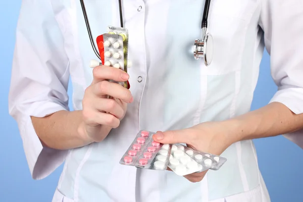 Primer plano de las píldoras de la mano del médico femenino, sobre fondo de color — Foto de Stock