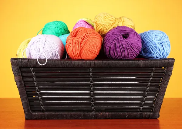 Palline di filato colorato in cestino su sfondo colore — Foto Stock