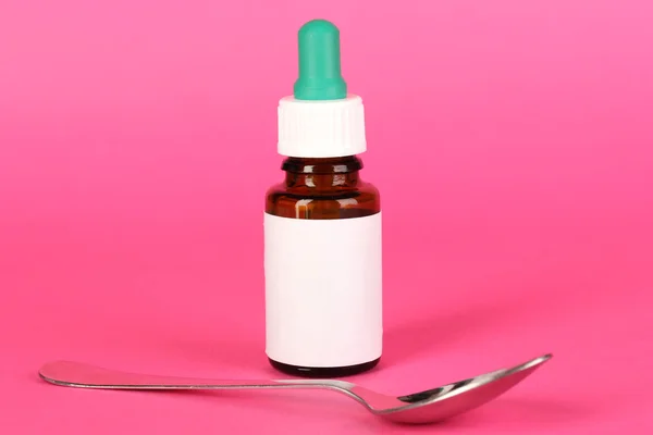 Medizinische Tropfen und Löffel für sie auf rosa Hintergrund — Stockfoto