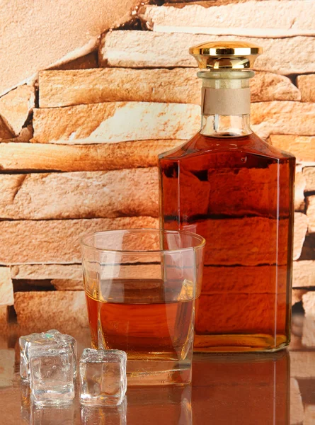 Бутылка и стакан виски и льда на фоне кирпичной стены — стоковое фото