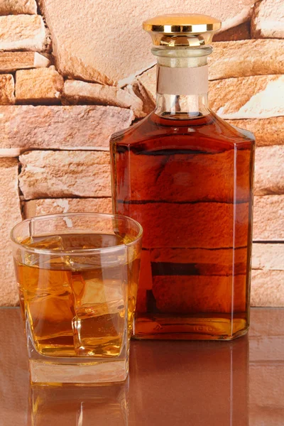 Bouteille et verre de whisky et de glace sur fond de mur de briques — Photo